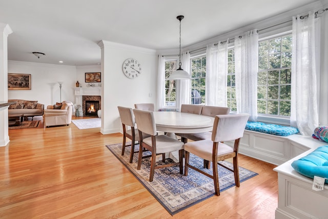 dining space featuring crown molding, light hardwood / wood-style floors, and a high end fireplace