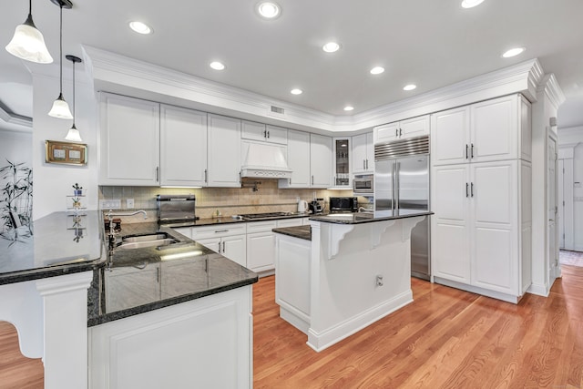 kitchen featuring light hardwood / wood-style floors, sink, custom range hood, a kitchen breakfast bar, and stainless steel appliances