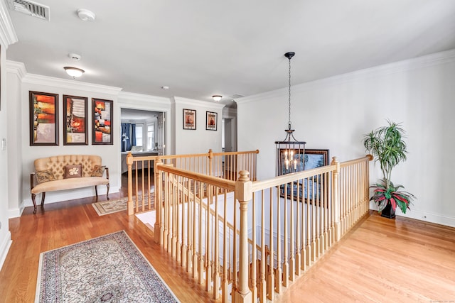 hall with an inviting chandelier, hardwood / wood-style flooring, and crown molding