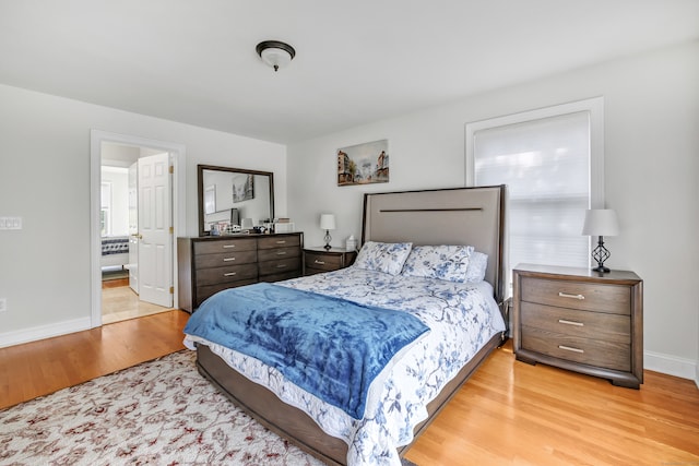 bedroom with ensuite bath and light hardwood / wood-style flooring