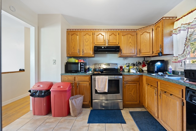 kitchen with light tile patterned floors, black appliances, and sink