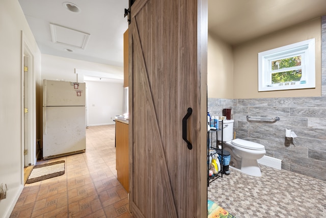 bathroom with toilet and tile walls