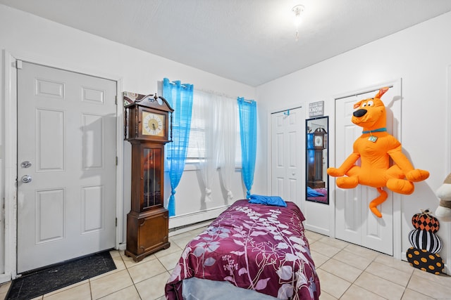 bedroom featuring a baseboard heating unit and light tile patterned floors