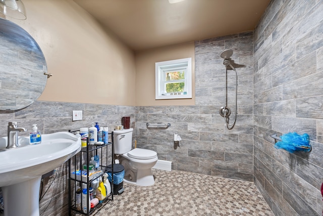 bathroom featuring toilet, tile walls, sink, and tiled shower