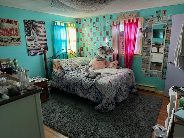 bedroom with a textured ceiling, baseboard heating, and hardwood / wood-style flooring