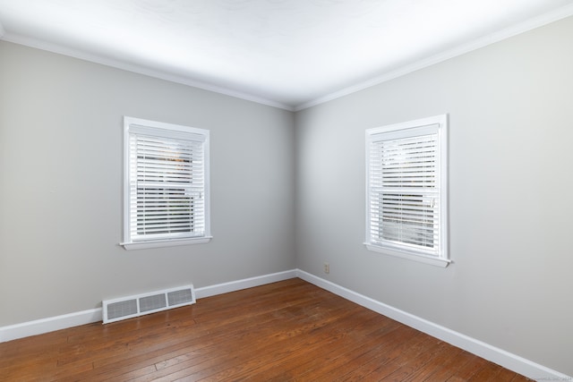 empty room featuring crown molding, dark hardwood / wood-style floors, and a wealth of natural light