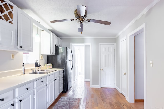 kitchen featuring sink, white cabinets, light hardwood / wood-style flooring, and a textured ceiling