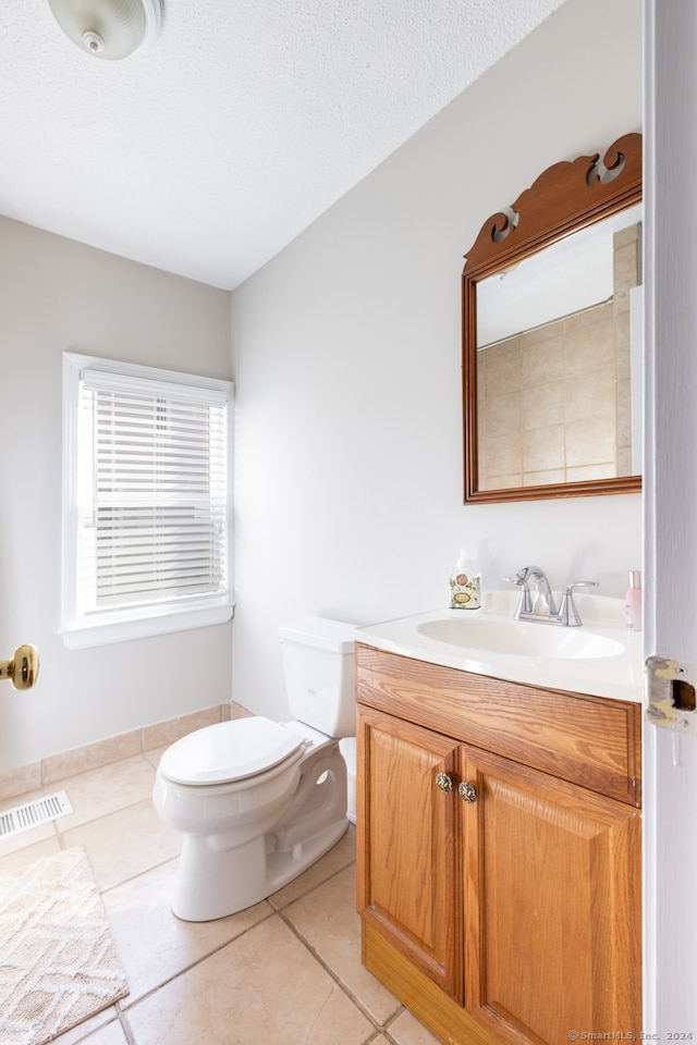 bathroom featuring vanity, toilet, a textured ceiling, and tile patterned flooring