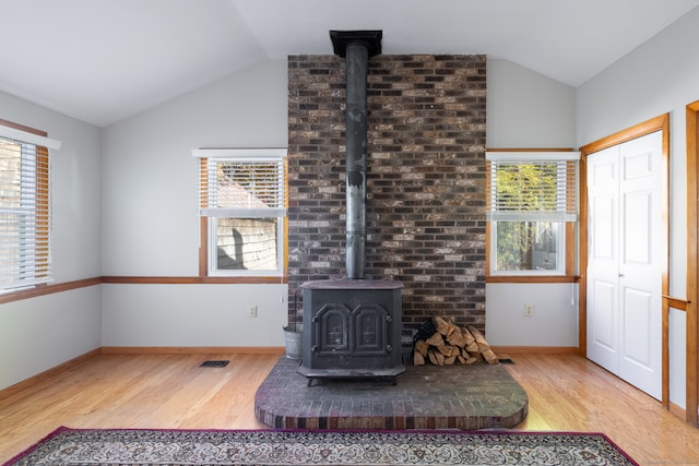 living room with a wood stove, hardwood / wood-style flooring, and lofted ceiling