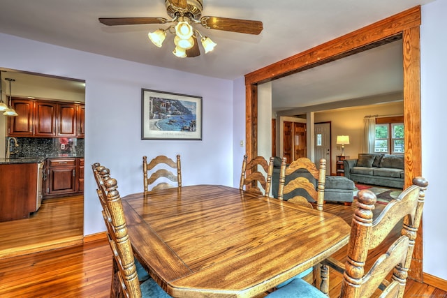 dining area with ceiling fan, dark hardwood / wood-style floors, and sink