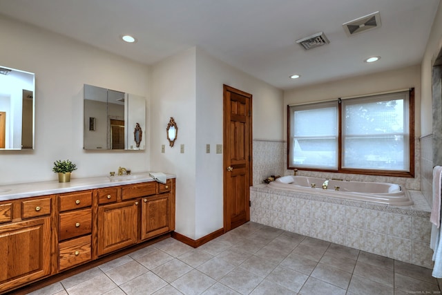 bathroom with tile patterned floors, tiled tub, and vanity