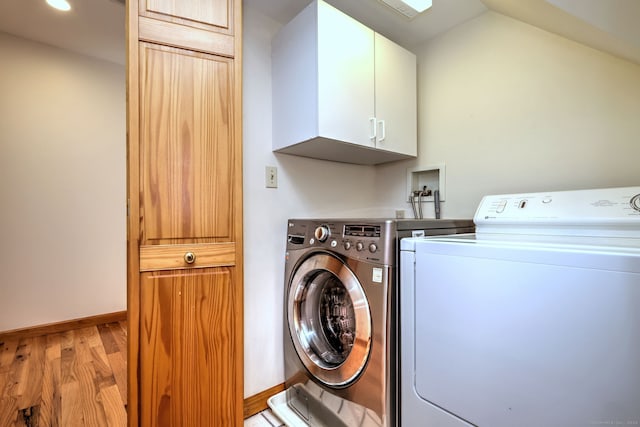 washroom featuring cabinets, light hardwood / wood-style floors, and washer and dryer