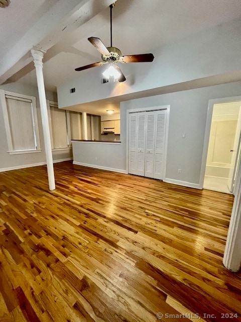 unfurnished living room with ceiling fan, light wood-type flooring, and decorative columns