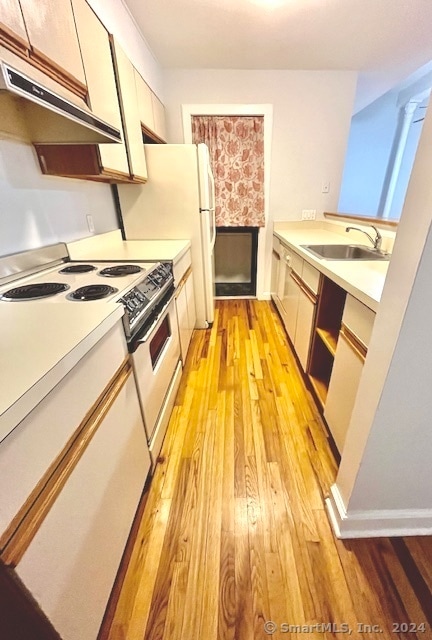 kitchen featuring white cabinets, sink, range with electric cooktop, a fireplace, and light wood-type flooring