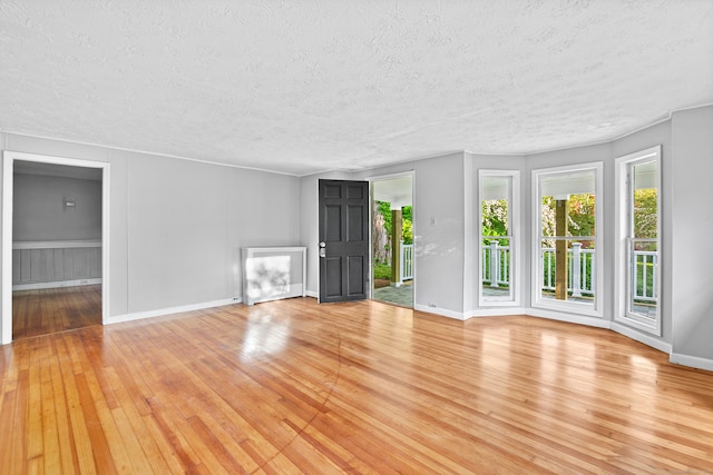 unfurnished living room featuring a textured ceiling and light hardwood / wood-style flooring