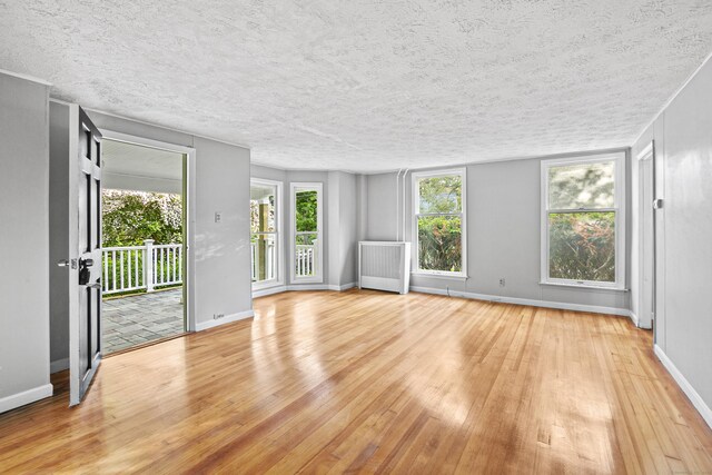 spare room featuring light wood-type flooring, a textured ceiling, and radiator