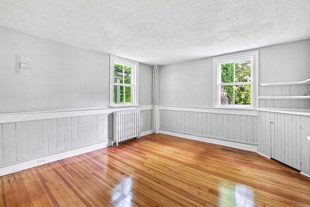 spare room featuring radiator, a textured ceiling, and hardwood / wood-style floors