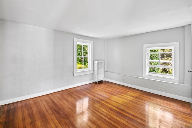 spare room with radiator, hardwood / wood-style floors, and a healthy amount of sunlight