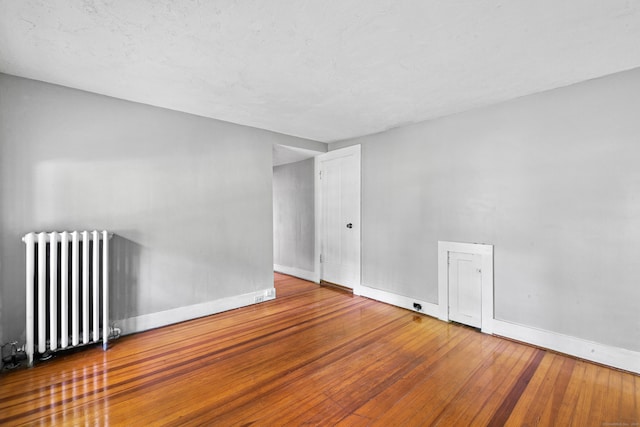 empty room featuring hardwood / wood-style floors and radiator heating unit