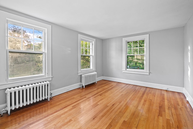 unfurnished room with light wood-type flooring, a healthy amount of sunlight, and radiator