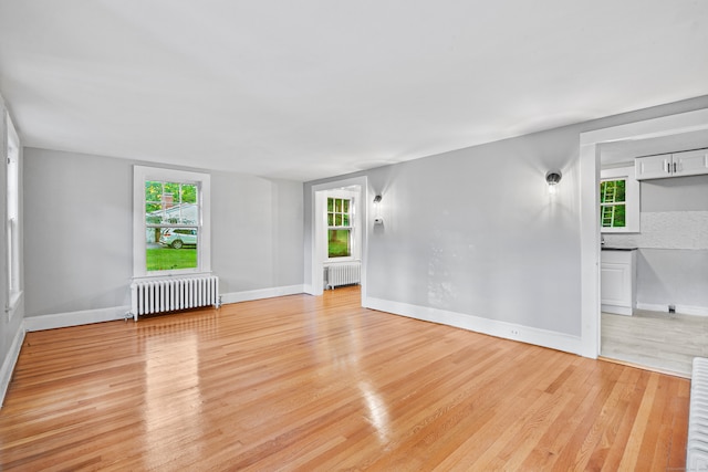 unfurnished room with light wood-type flooring and radiator heating unit