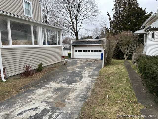 view of home's exterior with a garage, a sunroom, and an outdoor structure