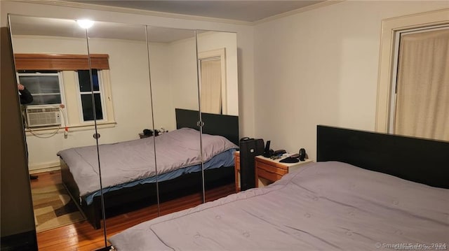 bedroom with a closet, cooling unit, wood-type flooring, and ornamental molding