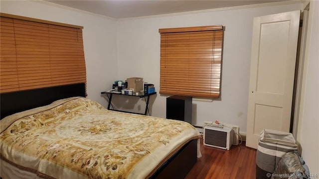 bedroom with dark hardwood / wood-style flooring and crown molding