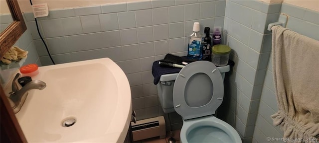 bathroom featuring sink, toilet, a baseboard heating unit, and tile walls