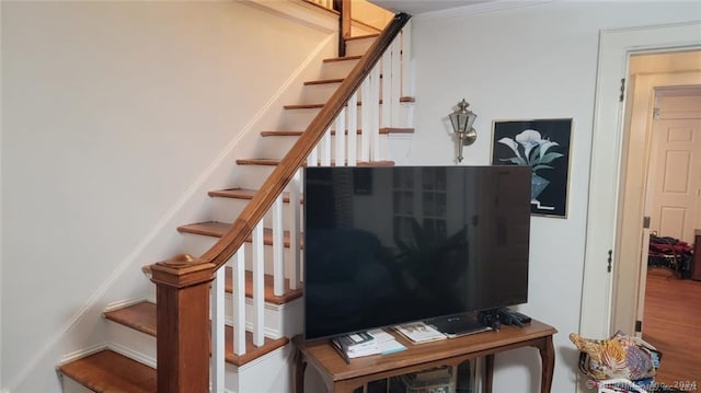 stairs featuring ornamental molding and hardwood / wood-style floors