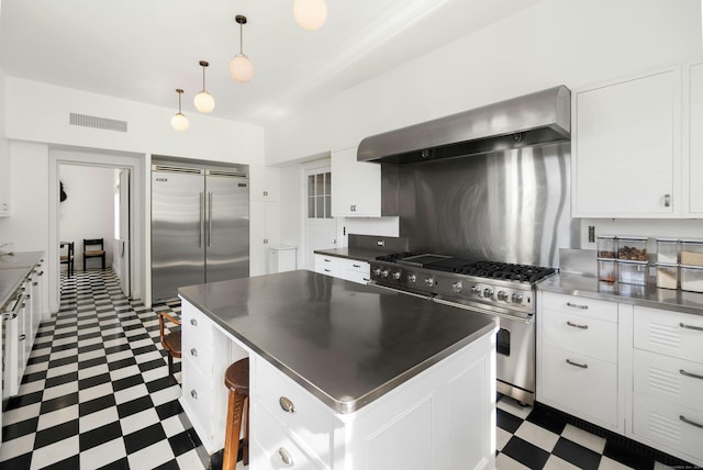 kitchen with premium appliances, a kitchen island, range hood, decorative light fixtures, and white cabinetry