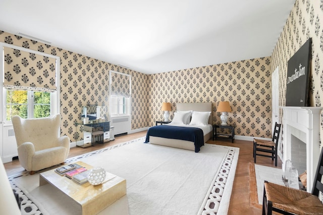 bedroom with wood-type flooring and a brick fireplace