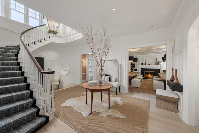 9 Cowdray Park Dr, Greenwich, CT 06831 - foyer with a towering ceiling, ornamental molding, a warm lit fireplace, stairs, and a decorative wall