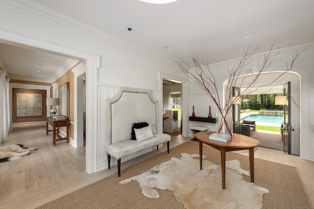 living area with crown molding and light hardwood / wood-style flooring