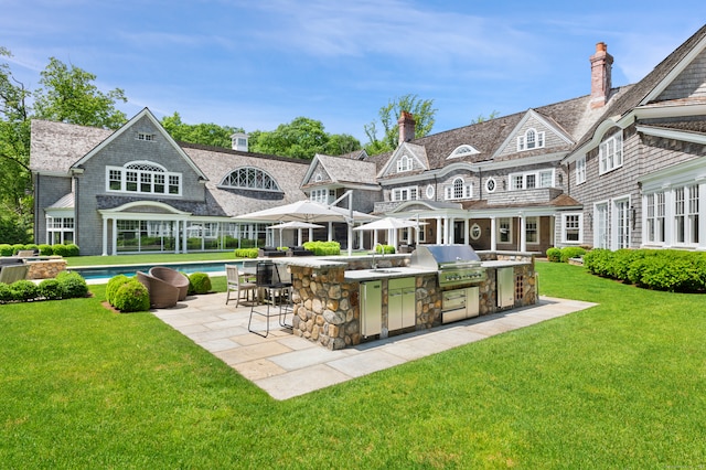 rear view of house featuring sink, a yard, a patio area, and exterior kitchen