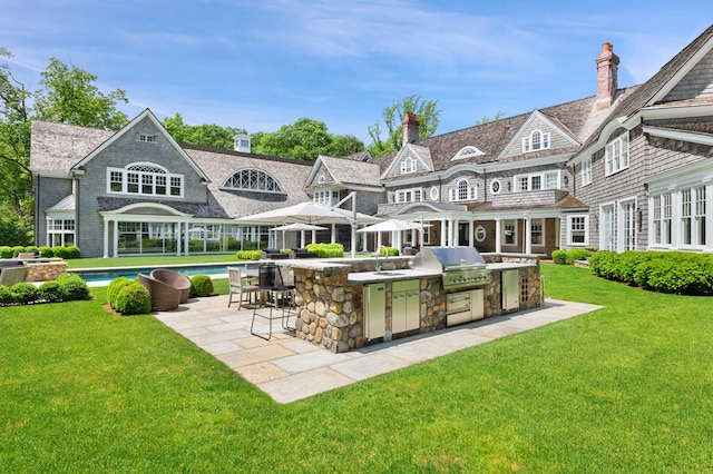 9 Cowdray Park Dr, Greenwich, CT 06831 - rear view of property featuring a patio, an outdoor kitchen, an outdoor pool, stone siding, and a yard