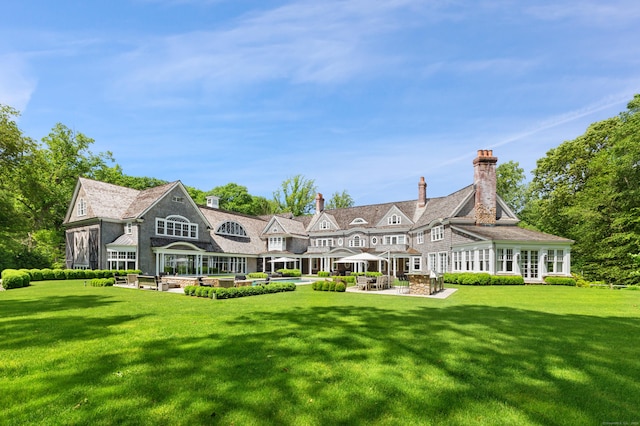 9 Cowdray Park Dr, Greenwich, CT 06831 - back of property featuring a yard, a chimney, and a patio area
