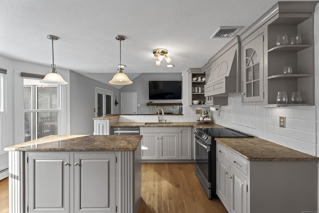 kitchen featuring sink, stainless steel range with electric cooktop, a center island, kitchen peninsula, and pendant lighting