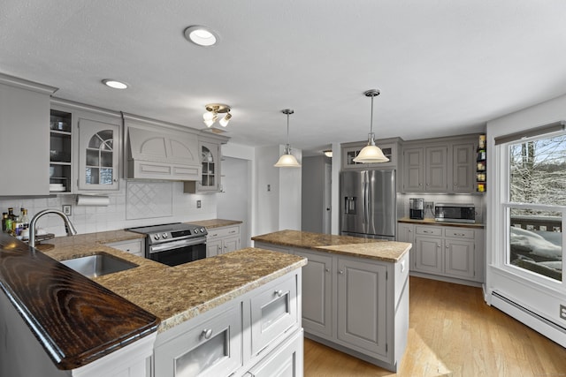 kitchen featuring appliances with stainless steel finishes, sink, custom exhaust hood, a center island, and baseboard heating