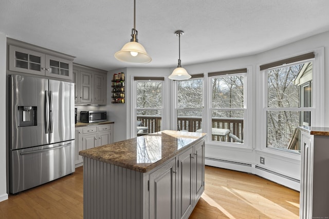 kitchen with appliances with stainless steel finishes, gray cabinetry, a baseboard heating unit, a center island, and light wood-type flooring