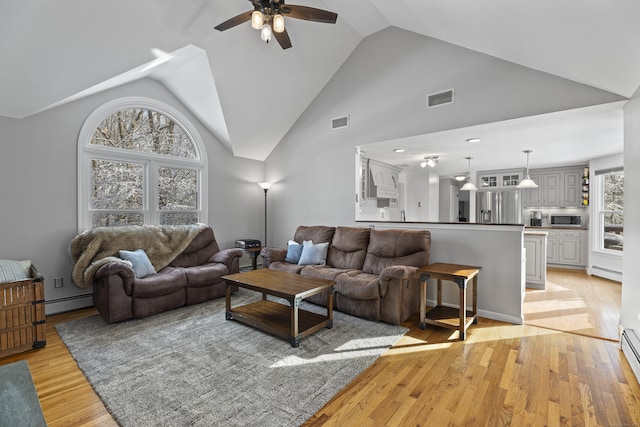 living room with ceiling fan, high vaulted ceiling, a baseboard heating unit, and light hardwood / wood-style floors