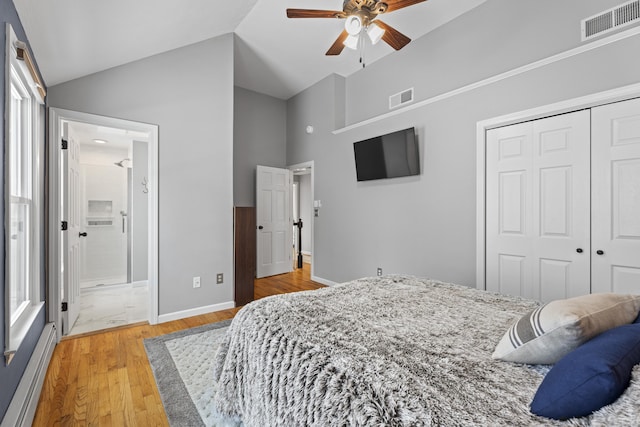 bedroom with hardwood / wood-style flooring, baseboard heating, ensuite bathroom, vaulted ceiling, and a closet