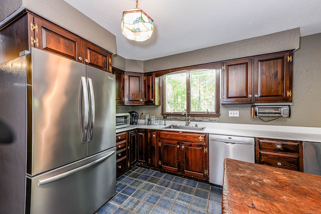 kitchen with sink, dark brown cabinets, a textured ceiling, decorative light fixtures, and appliances with stainless steel finishes