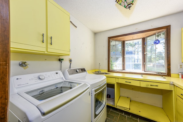 laundry room featuring a textured ceiling, washer and clothes dryer, sink, and cabinets