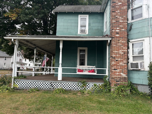 exterior space with cooling unit, a front lawn, and covered porch