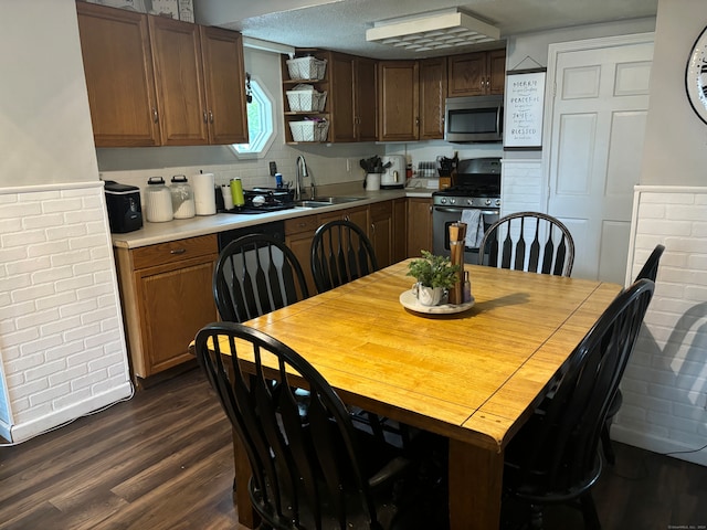 kitchen with sink, a textured ceiling, stainless steel appliances, dark hardwood / wood-style floors, and decorative backsplash