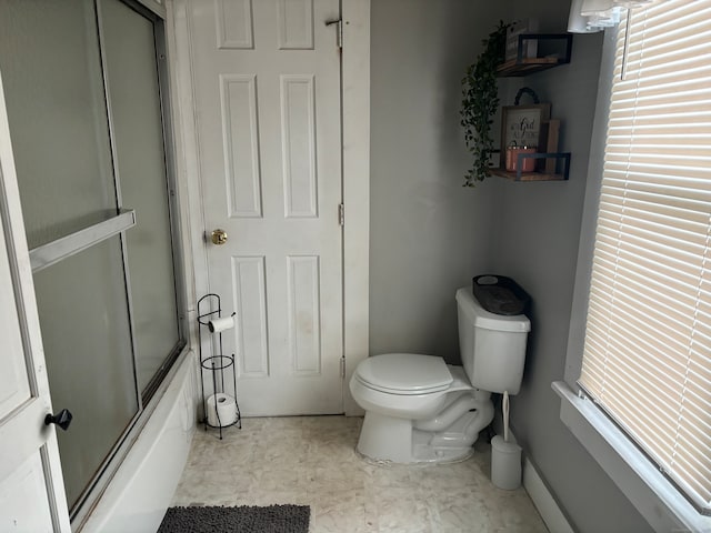 bathroom with bath / shower combo with glass door, toilet, and plenty of natural light