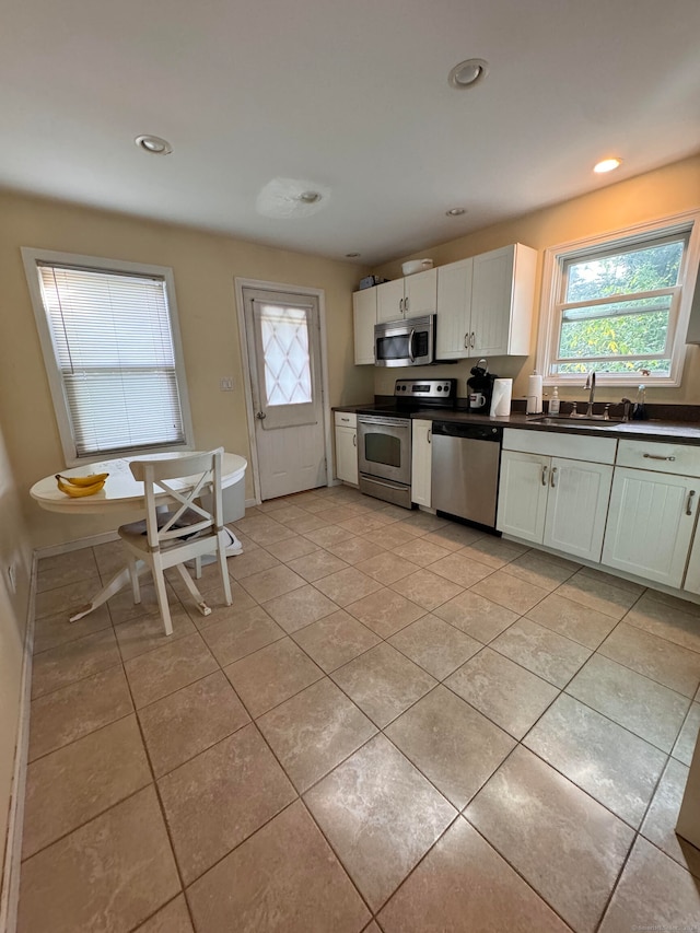 kitchen with white cabinetry, appliances with stainless steel finishes, light tile patterned flooring, and sink