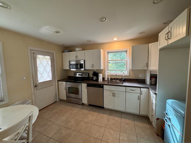 kitchen with white cabinets, appliances with stainless steel finishes, light tile patterned flooring, and sink