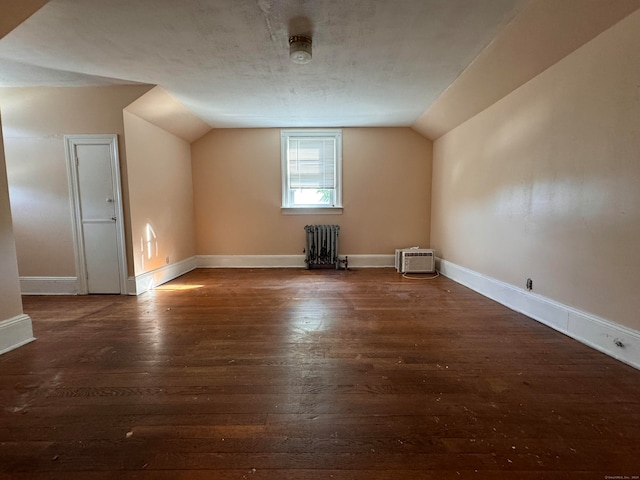 bonus room with an AC wall unit, radiator, lofted ceiling, and dark hardwood / wood-style flooring